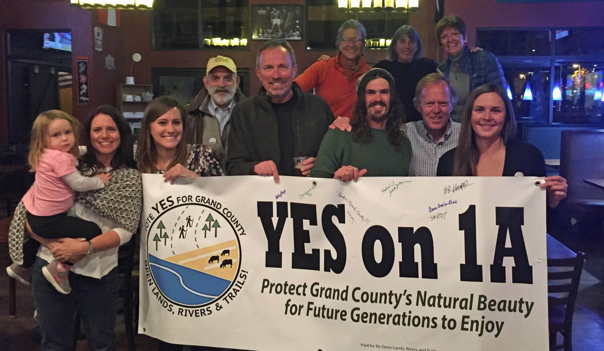 Meara and group holding a banner for Yes on 1A